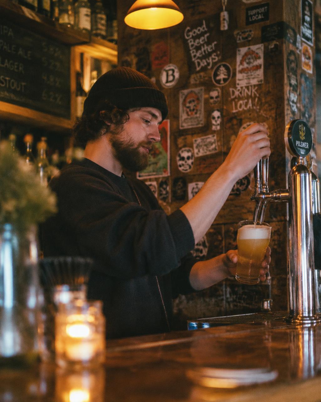 Barman čapuje pivo pri drevenom bare
